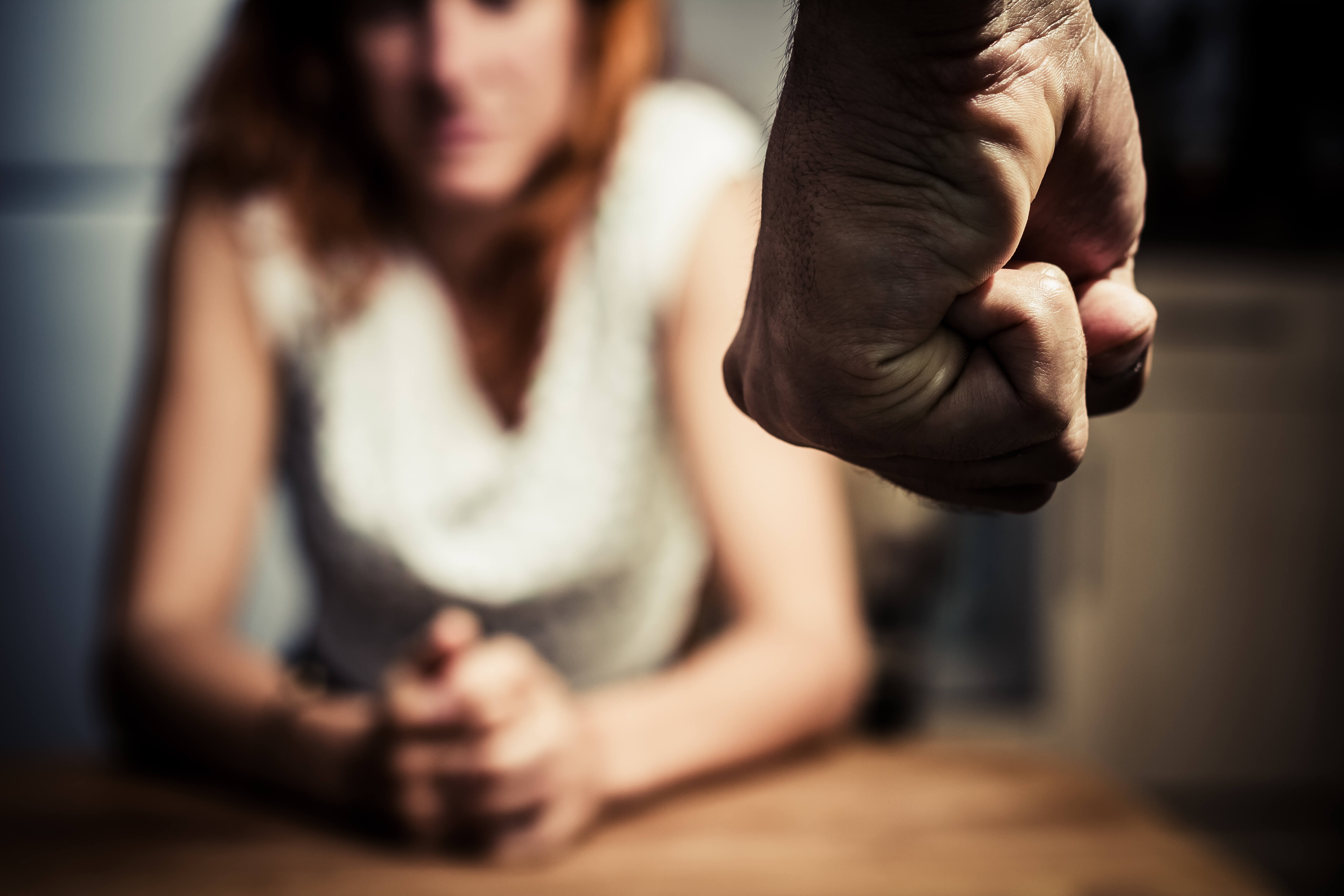 Man approaching a woman with his fist raised